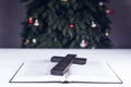 An open Bible on the table. Prayer. Wooden cross. Crucifix. Holy. On the background of the Christmas tree. Light and garlands Royalty Free Stock Photo