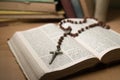 An open bible with a wooden and metal crucifix, with other old books in the blurred background Royalty Free Stock Photo
