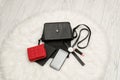 Open black bag with dropped things, notebook, mobile phone, watch, red purse and lipstick. The white fur on background, top view. Royalty Free Stock Photo