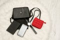 Open black bag with dropped things, notebook, mobile phone, watch and red purse. The white fur on background, top view. Royalty Free Stock Photo