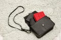 Open black bag with things, mobile phone, red purse. Gray fur on background. Fashion concept Royalty Free Stock Photo