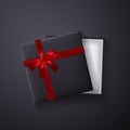 Open black empty gift box with red bow and ribbon on dark background. Top view. Template for your presentation, banner or poster. Royalty Free Stock Photo