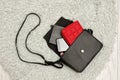 Open black handbag, red purse, mobile phone and lipstick in it. Grey fur background, top view. fashion concept Royalty Free Stock Photo