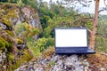 An open black laptop stands on a rock.