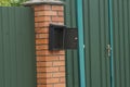 An open black mailbox hangs on the brown bricks of the fence
