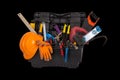 An open black plastic tool kit box with an orange protective helmet and various hand tools isolated on a black background close up Royalty Free Stock Photo