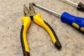 Open black and yellow pliers blue screwdriver closeup background building design web site