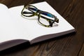 Open blank book, pen and glasses on dark wooden table. View from above. Space for text. closedup Royalty Free Stock Photo