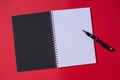 Open blank notebook with black cover on red background