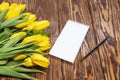 Open blank notebook and a bouquet of yellow tulips on a wooden table, top view. Women`s work Desk. The eighth of March. Holiday.