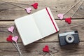 Open blank notebook with a vintage camera and hearts on an old w Royalty Free Stock Photo