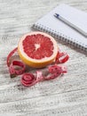 Open a blank Notepad, grapefruit and measuring tape on a light wooden table. The concept of healthy nutrition, diets