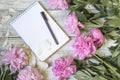 Open blank notepad, pen, and peony on the white wooden table. romantic flat lay. Royalty Free Stock Photo