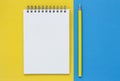 Open blank notepad with a yellow pencil on a blue and yellow background