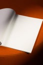 open blank page of a notebook or magazine rests on a soft orange surface Royalty Free Stock Photo