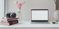 Open blank screen laptop computer with camera with roses vase and coffee cup