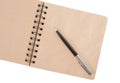 Open blank square notebook of brown kraft paper with a spiral and ballpoint pen lie on a white background Royalty Free Stock Photo