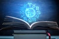 Open book on astrology on a dark background. The glowing magical globe with signs of the zodiac in the blue light Royalty Free Stock Photo