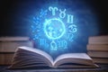 Open book on astrology on a dark background. The glowing magical globe with signs of the zodiac in the blue light Royalty Free Stock Photo