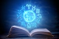 Open book on astrology on a dark background. Glowing magical globe with signs of the zodiac in the blue light Royalty Free Stock Photo