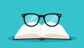 Open book with black-framed glasses resting on top against a tea Royalty Free Stock Photo