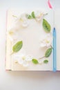 Open book with blank sheets and a blue pen. Fresh apple flowers and green leaves on paper sheet Royalty Free Stock Photo