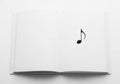 An open book with blank white pages features a single black eighth note symbol printed on the right Royalty Free Stock Photo