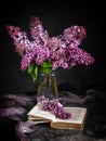Open book and a bouquet of lilacs on a dark background.