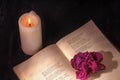 An open book with a candle. on the pages is a Bud of dried rose. Royalty Free Stock Photo