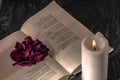 An open book with a candle. on the pages is a Bud of dried rose. Royalty Free Stock Photo