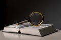 Open book closeup with turning pages and magnifying loupe. Textbook in hard cover on table. Studying and research Royalty Free Stock Photo