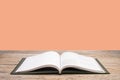 open book. Composition with hardback books, fanned pages on wooden deck table and orange background. Books stacking. Back to Royalty Free Stock Photo