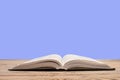 open book. Composition with hardback books, fanned pages on wooden deck table and purple background. Books stacking. Back to Royalty Free Stock Photo