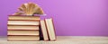 open book. Composition with hardback books, fanned pages on wooden deck table and purple background. Books stacking. Back to Royalty Free Stock Photo