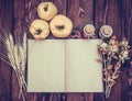 Open book with empty pages on an autumn background. Quince, wheat, dried herbs, bottles and an open book on wooden board. Royalty Free Stock Photo