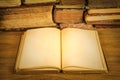 Open book with empty pages on a wooden table in front of a pile of old weathered books Royalty Free Stock Photo