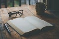 Open Book, Glasses, Pen, and Cup on Wooden Table Royalty Free Stock Photo