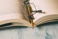 Open book with glasses and pencil on wooden table as background. Education, wisdom and study concept. Royalty Free Stock Photo