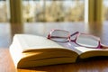 Open book and glasses on a wooden table with sunlight Royalty Free Stock Photo