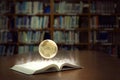 An open book glows brightly and reveals a globe of the world, in old self of book library university background among Royalty Free Stock Photo