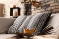Open book with golden origami boat on comfortable sofa
