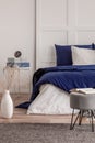 Open book on grey pouf in trendy bedroom interior with blue and white design