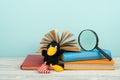 Open book, hardback colorful books on wooden table. Magnifier, toy crow. Back to school. Copy space for text. Education Royalty Free Stock Photo