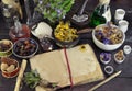 Open book with herbs, berries and flowers on witch table