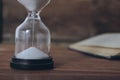 open book and hourglass on a wooden table Royalty Free Stock Photo