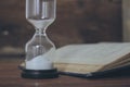 open book and hourglass on a wooden table Royalty Free Stock Photo