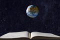 An open book, a levitating model of the planet earth levitates above it, against the background of outer space with stars. The Royalty Free Stock Photo