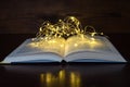 Open book light of a garland in the dark wooden