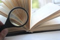 Open book with magnifying glass over nature background. knowledge concept Royalty Free Stock Photo