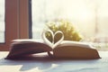 Open book with pages shaped as heart on wooden table Royalty Free Stock Photo